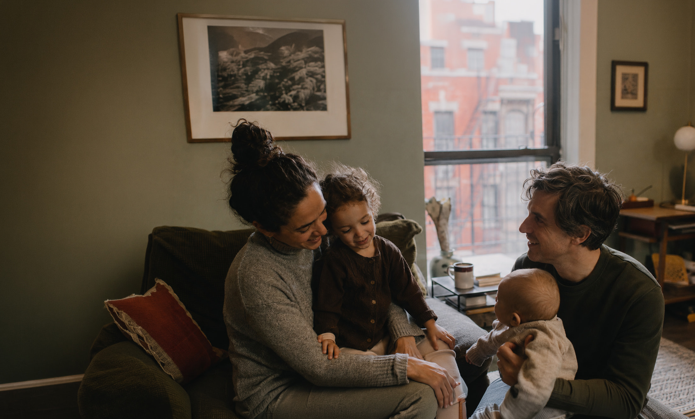 Two smiling parents at home with their toddler and baby